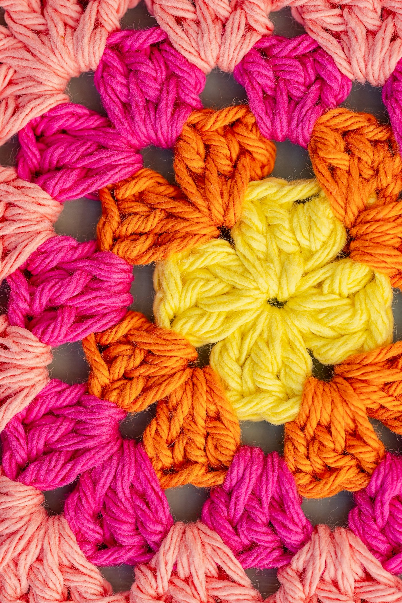 Close-up of a chunky granny square with a yellow center and orange and pink rounds