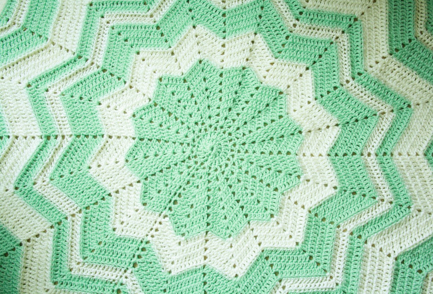 A mint green and white crocheted star-shaped blanket