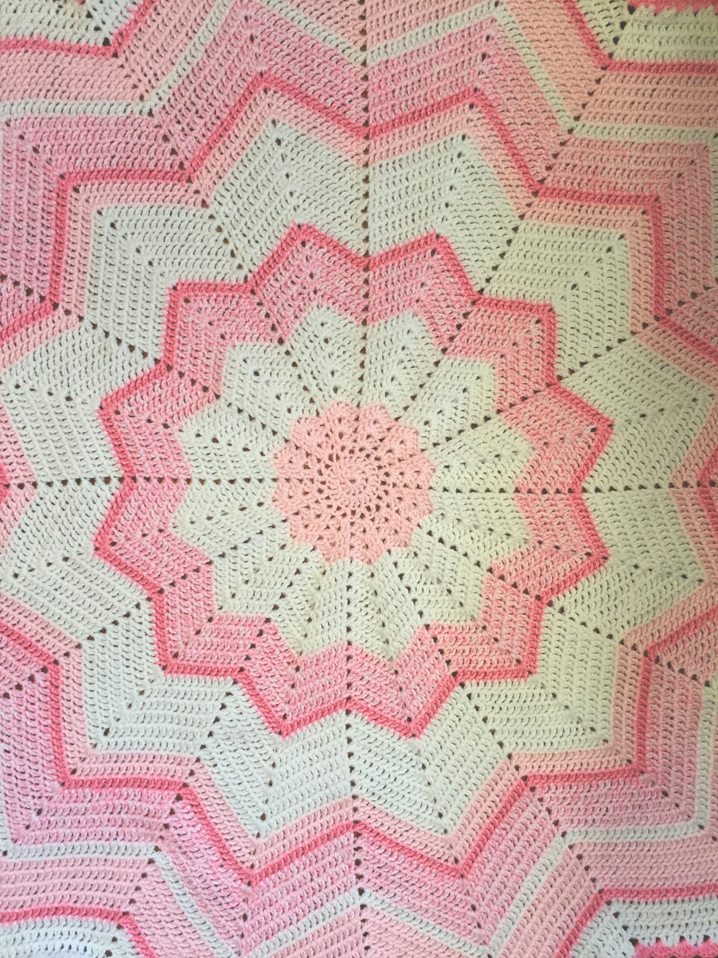 A pink and white crocheted star-shaped blanket