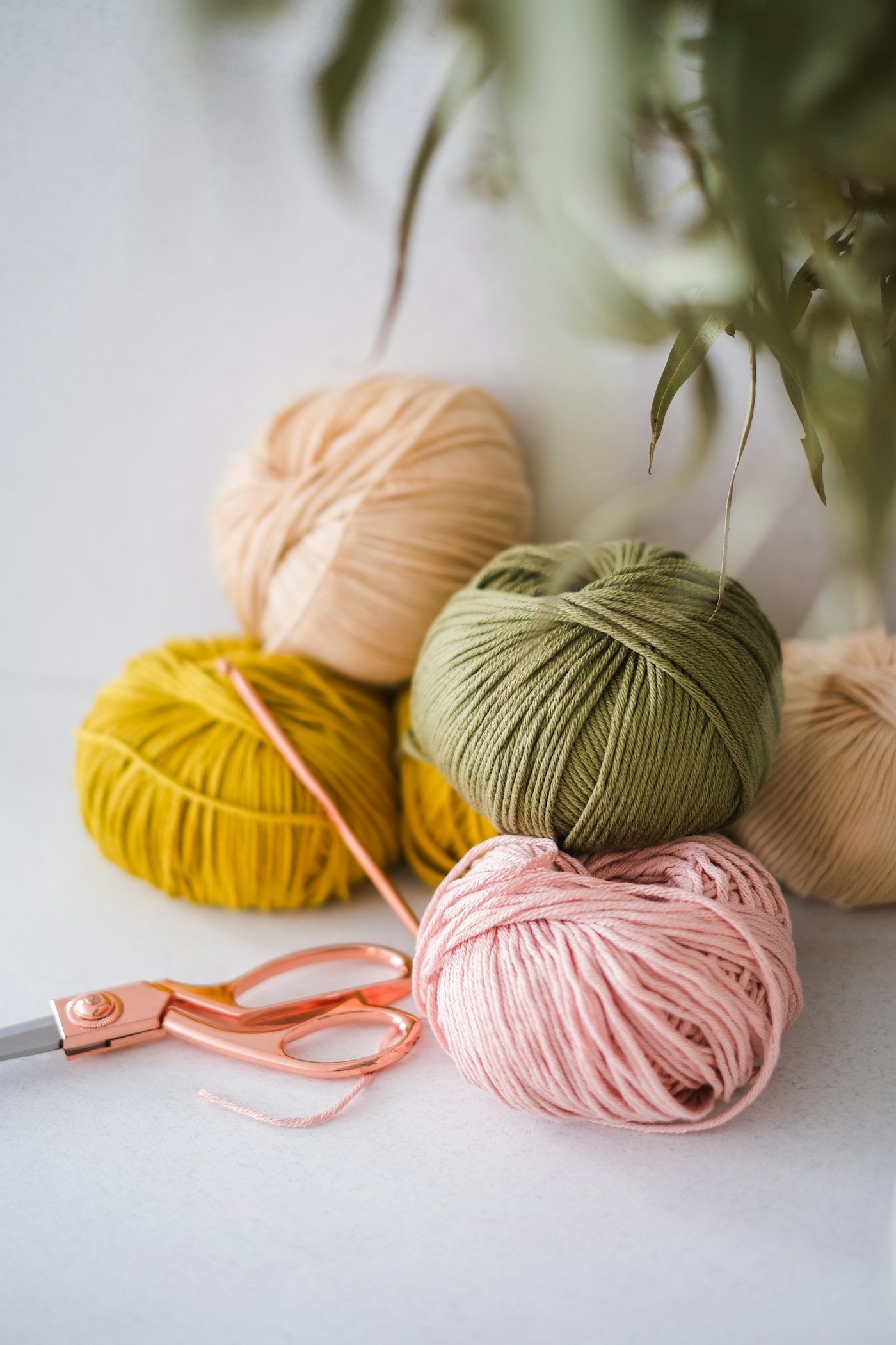 Balls of mustard, olive, peach and pink cotton yarn