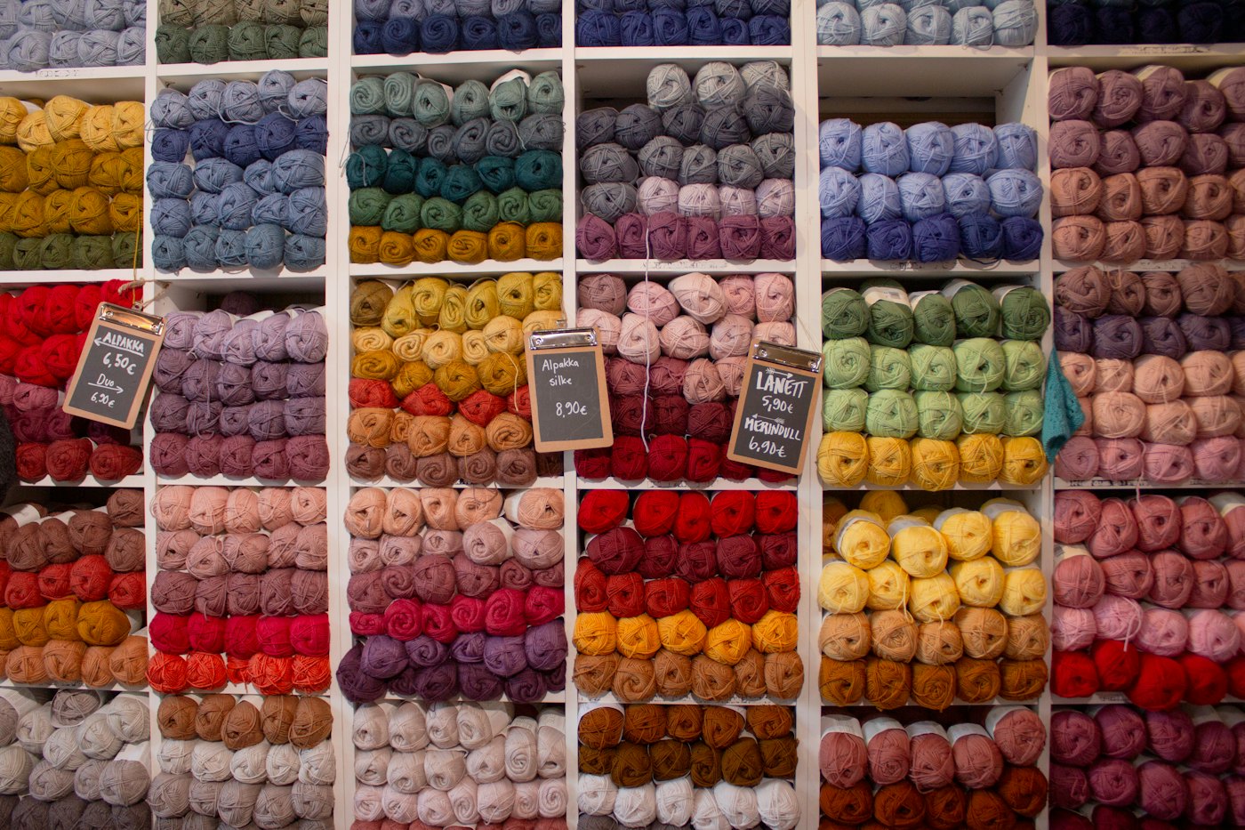 A wall of yarn shelves sorted by color in a yarn shop