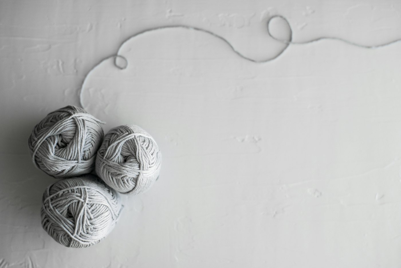 Three grey yarn balls on a white surface